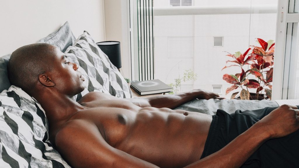 Homem a descansar numa cama moderna, com um livro ao seu lado