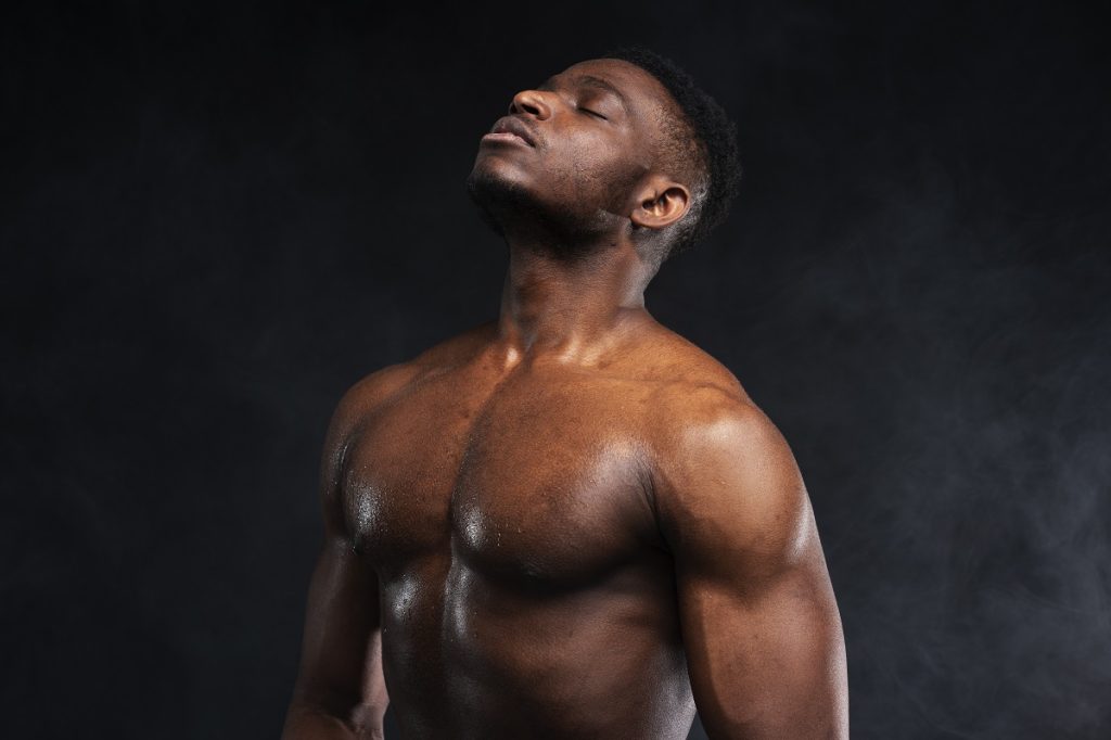 Homem musculado a refletir num estúdio escuro