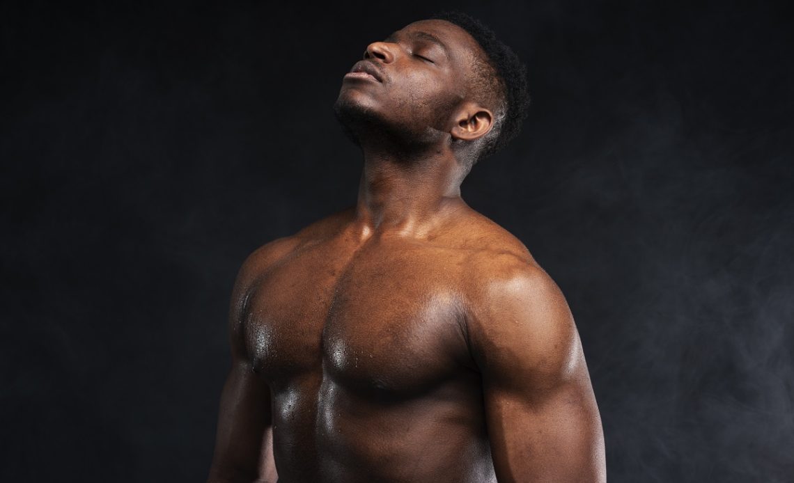 Homem musculado a refletir num estúdio escuro