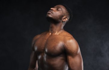 Muscular man reflecting in dark studio