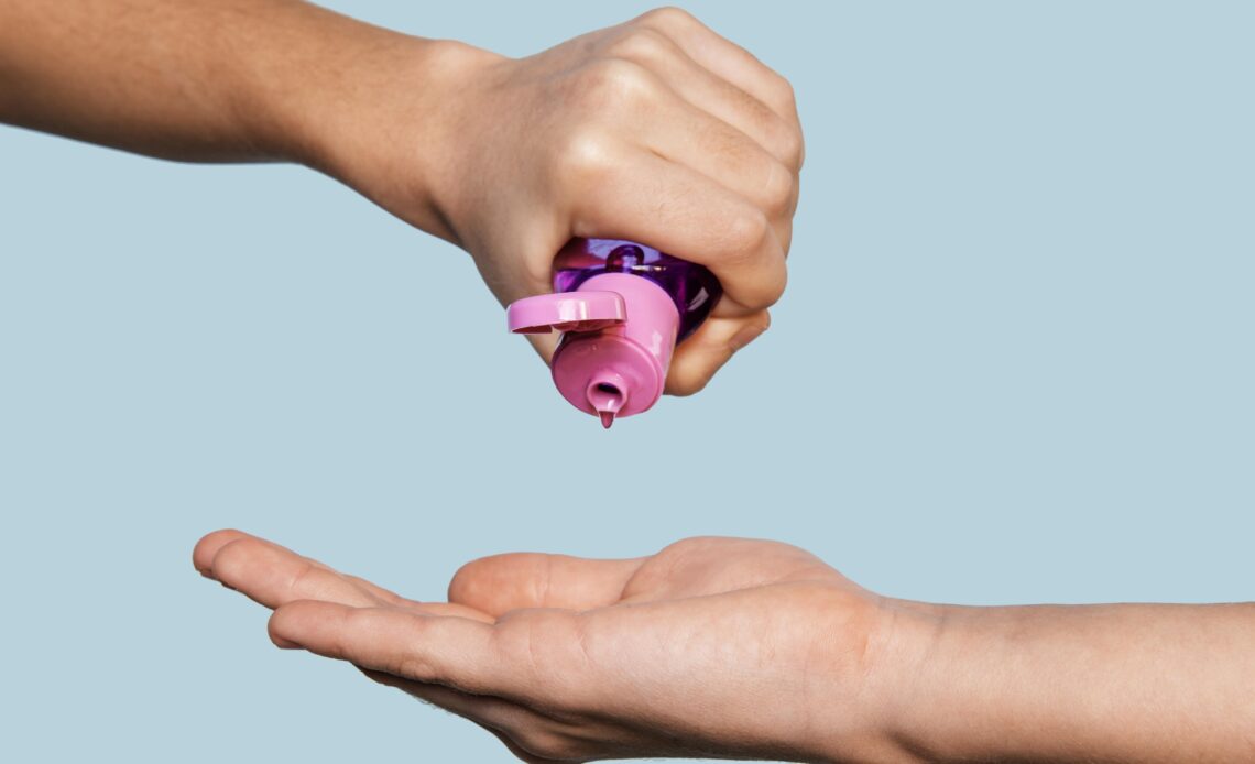 Hand squeezing pink lubrifiant onto another hand