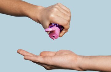 Hand squeezing pink lubrifiant onto another hand