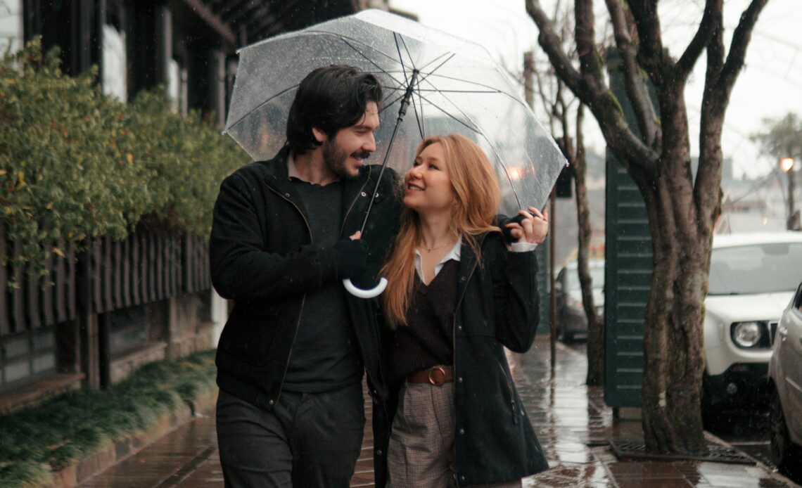 Couple marchant sous la pluie avec un parapluie transparent
