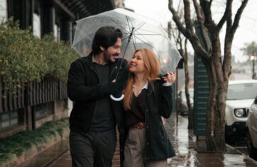 Paar loopt in de regen met een transparante paraplu