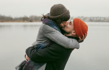 Couple kissing by lake wearing colorful hats
